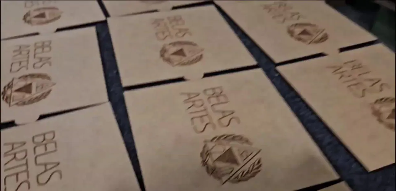 Tampas de MDF gravadas com o logo da Belas Artes, alinhadas na bancada