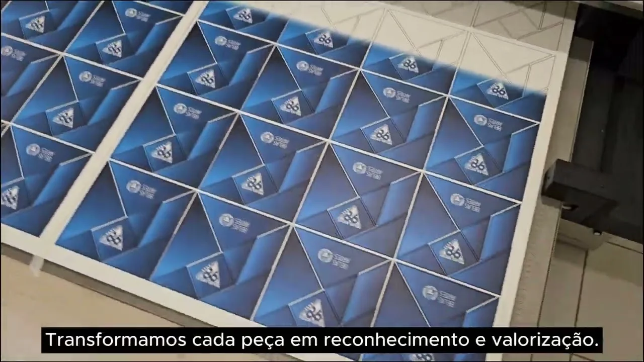 Impressora UV imprimindo peças com o logo de 98 anos da Belas Artes